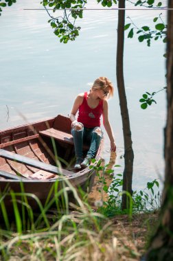 Yaz aylarında göl kıyısı bir teknede genç sarışın kız