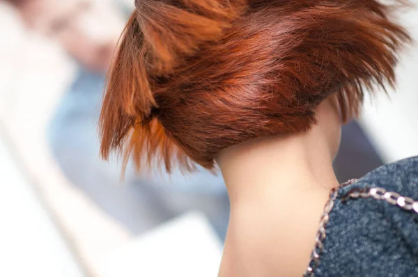 Accurate geometric shape short haircut on a woman with red hair in detail