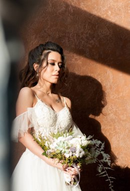 bir buket çiçek ile beyaz bir gelinlikle koyu saçlı gelin