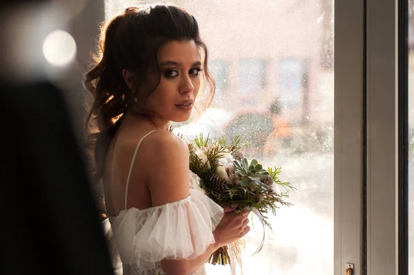 bride with dark hair in a white wedding dress with a bouquet of flowers