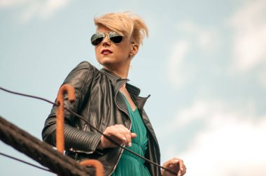 bir kız bir kısa saç kesimi ve sarı saçlı mavi gökyüzünde Bahar yakın çekim karşı köprüde portresi