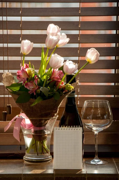gift, bouquet of flowers and wine with a note on the windowsill