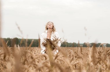Bir buğday tarlasında mısır kulakları ile sarışın kadın