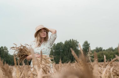Bir buğday tarlasında şapkalı sarışın kadın