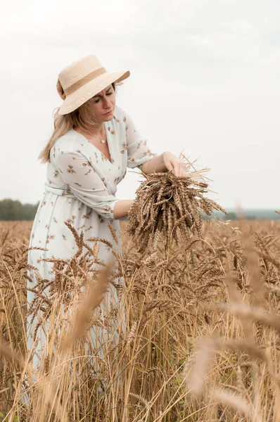 Bir buğday tarlasında şapkalı sarışın kadın