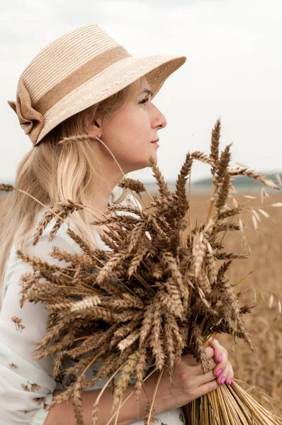 Bir buğday tarlasında şapkalı sarışın kadın