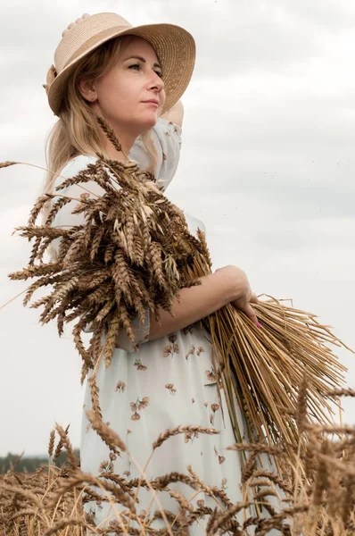Bir buğday tarlasında şapkalı sarışın kadın