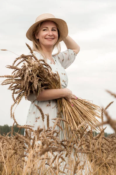 Bir buğday tarlasında şapkalı sarışın kadın