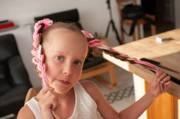 Handmade elastic hair band with colored pigtails made of artificial hair on a little girl