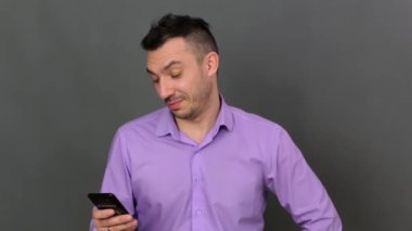 Mutlu bir genç adam telefonuna bakar..