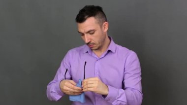 Genç bir adam gözlüğünü paçavrayla siler..