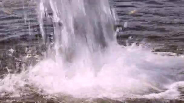 A powerful stream of water falls into a body of water. — Stock Video