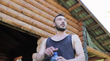 Şişeden su içen siyah tişörtlü bir adamın alt görüntüsü..