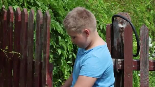 El chico abre una puerta de madera y sale . — Vídeos de Stock