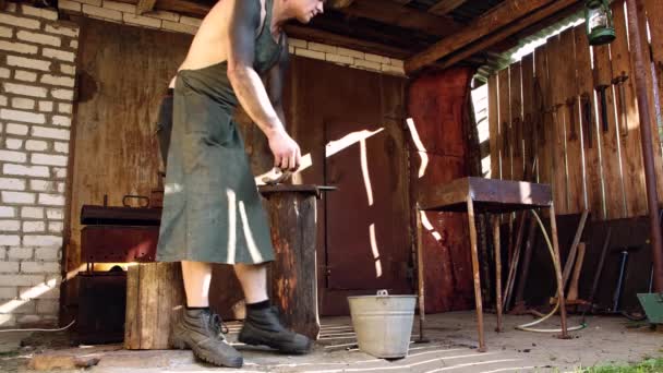 Mladý muž v pracovních šatech a potřísněný sazemi sedí na kládě — Stock video