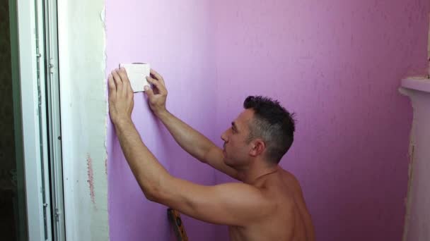 Ο εργάτης πιέζει απαλά τα πλακάκια στον τοίχο με τα χέρια του.. — Αρχείο Βίντεο