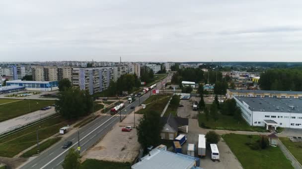 Kolumna ciężarówek jedzie wzdłuż drogi na obrzeżach miasta. — Wideo stockowe