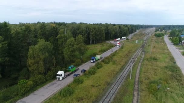 Kolumna ciężarówek jedzie wzdłuż krętej drogi wiejskiej. — Wideo stockowe