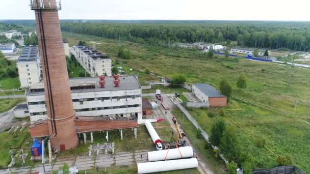 Flug eines Quadrocopters über eine Baustelle mit Schornstein. — Stockvideo