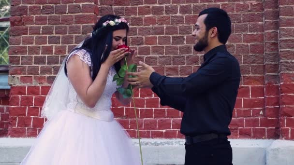 Девушка берет цветок у молодого человека и нежно нюхает его. — стоковое видео