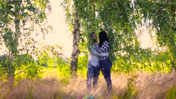 Młoda zakochana para całująca się pod liśćmi drzew. — Wideo stockowe