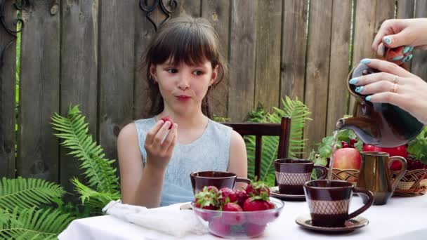 Una ragazza con un vestito blu sta mangiando una fragola. — Video Stock