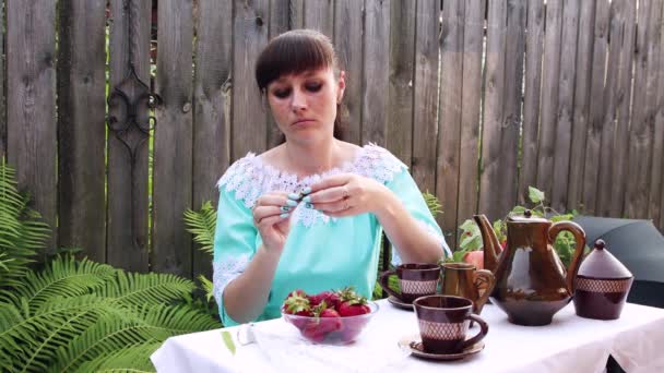 Una giovane donna esamina una bacca rossa, la mette in bocca e mangia — Video Stock