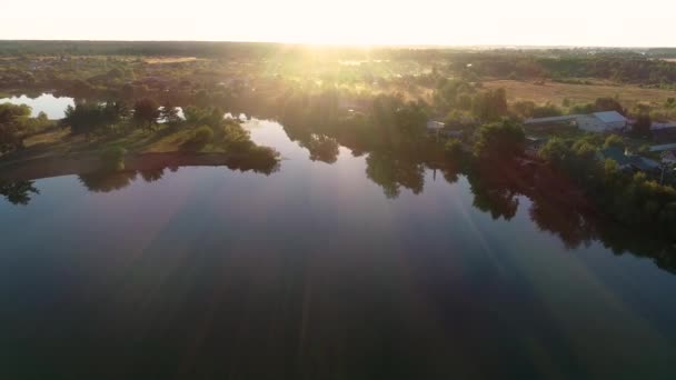 Lot na spotkanie słońca nad jeziorem i wsią. — Wideo stockowe