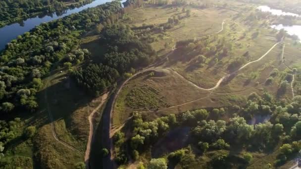 Filmagem aérea do campo com estradas de terra, lago, aldeia. — Vídeo de Stock
