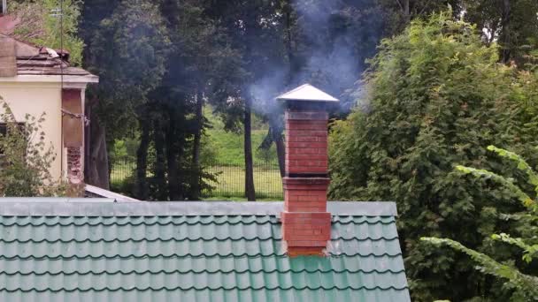 Rook afkomstig van een schoorsteen op het dak bedekt met groene tegels. — Stockvideo