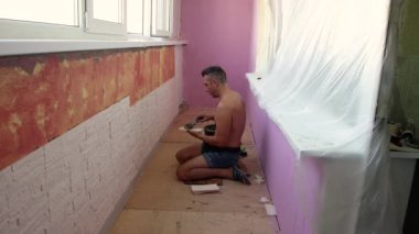 Yerde oturan genç bir adam fayanslara havan topu sürüyor..