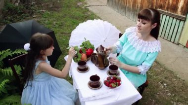 Anne ve kızı masaya oturmuş çay koyuyorlar..