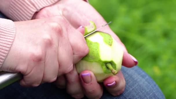 Kobiece dłonie z nożem obierają zieloną gruszkę ze skóry. — Wideo stockowe