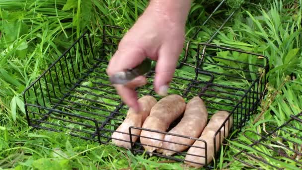 Mężczyzna ręce układają kiełbaski na grillu. — Wideo stockowe