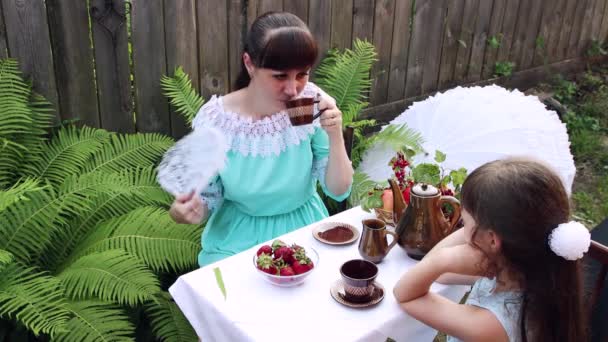 女性と女の子が果物やお茶とテーブルに座っています. — ストック動画