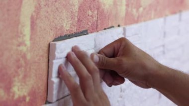 Erkek ellerinin duvara fayansları sabitlediği yakın plan.. 