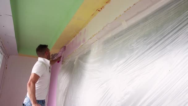 Een professionele werker schildert de muur roze. — Stockvideo