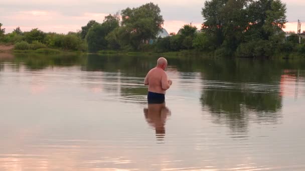 Un uomo entra nello stagno fresco e si tuffa. — Video Stock