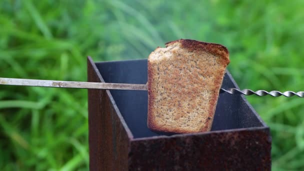 Een stuk zwart brood op een spies wordt gebakken op de grill. — Stockvideo