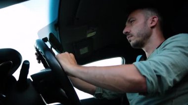 Arabada oturup bir şeyler konuşan bir adamın alt görüntüsü.