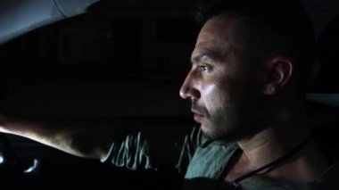 Amaçlı bir adamın yakın çekimi dinamik bir şekilde araba sürüyor..