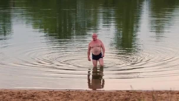 Mężczyzna wychodzi z jeziora po kąpieli.. — Wideo stockowe