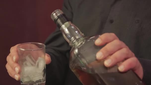 Gros plan mains masculines verser le whisky dans un verre avec de la glace — Video