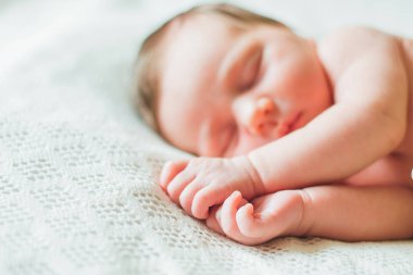 Yeni doğan bebek eller odaklanmak beyaz çarşafımda yatıyor 