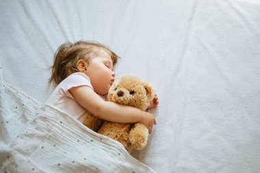 Küçük bebek yatakta uyuyan yumuşak oyuncak kucaklayan, boş alan