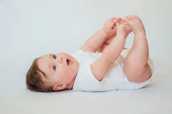 Little baby lying on back wearing white clothes on white background