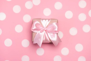 Pembe pastel arka planda konfeti ve kurdeleyle süslenmiş hediye kutusu ya da hediye. Kopyalama alanı olan üst görünüm. Doğum günü veya düğün için düz kompozisyon.