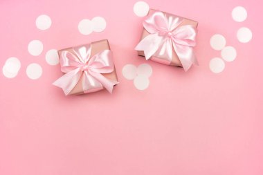 İki hediye ya da pembe pastel arka planda konfeti ile süslenmiş hediye kutuları. Kopyalama alanı olan üst görünüm. Doğum günü veya düğün için düz kompozisyon.