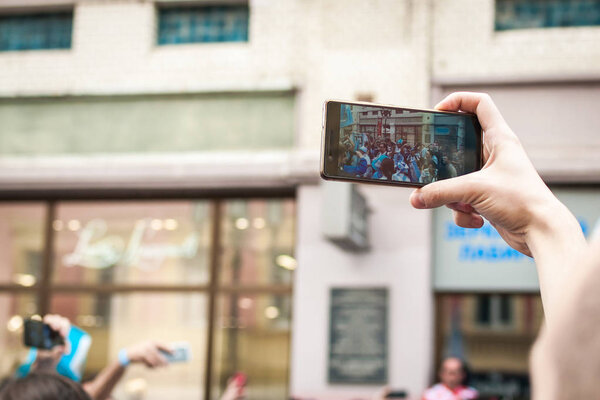 Shooting mobile phone with hands, against the crowd of peopl