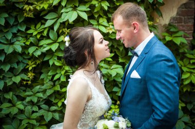 Gelin ve damat yeşil çiçek açan bir arka plan üzerinde genç çift